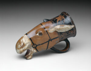 This drinking cup could not have been set down without its contents spilling. It is fashioned after the head of a bridled donkey with a white muzzle, teeth, and ears. Like the naked satyr chasing a fleeing maenad on the vessel’s neck, the donkey belongs to the retinue of the wine god Dionysos.